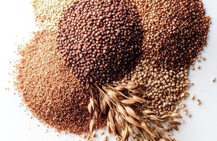 Assorted healthy millets and grains in wooden spoons